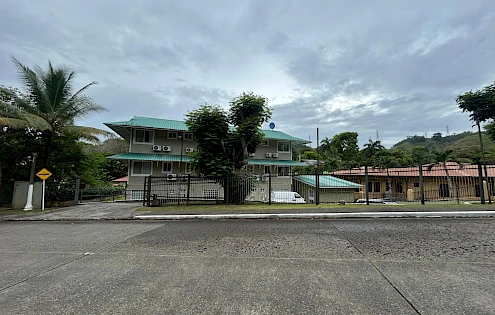 Edificio de tres pisos con 8 unidades y una casa pequeña.